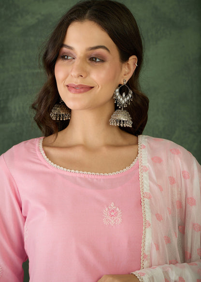 Woman wearing a pink traditional outfit with jewelry against a green background