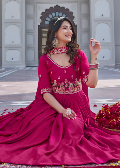 Woman in a pink traditional outfit sitting on a decorated ground with flowers and a building in the background