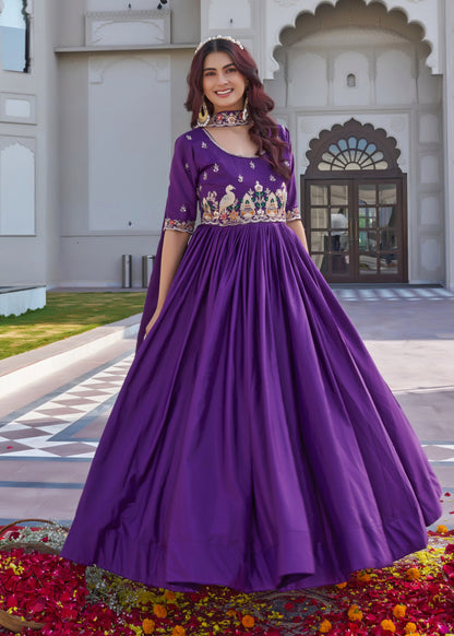 Woman in a purple embroidered dress standing in front of a decorative entrance.