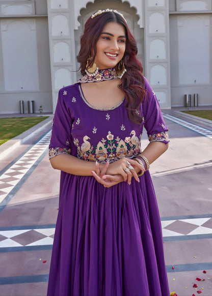 Woman in a purple dress with floral patterns standing in front of an architectural structure.