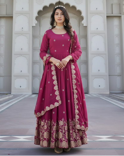 Woman in a pink traditional outfit standing in front of an architectural wall.