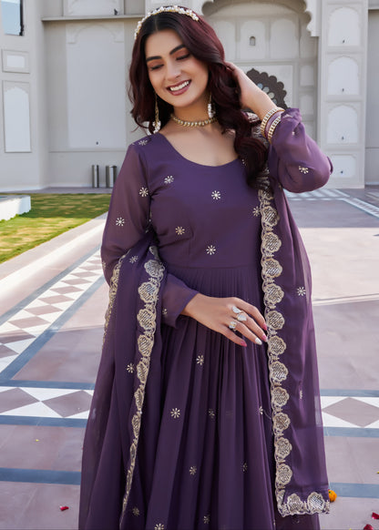 Woman in a purple traditional outfit with silver details standing in front of a building.